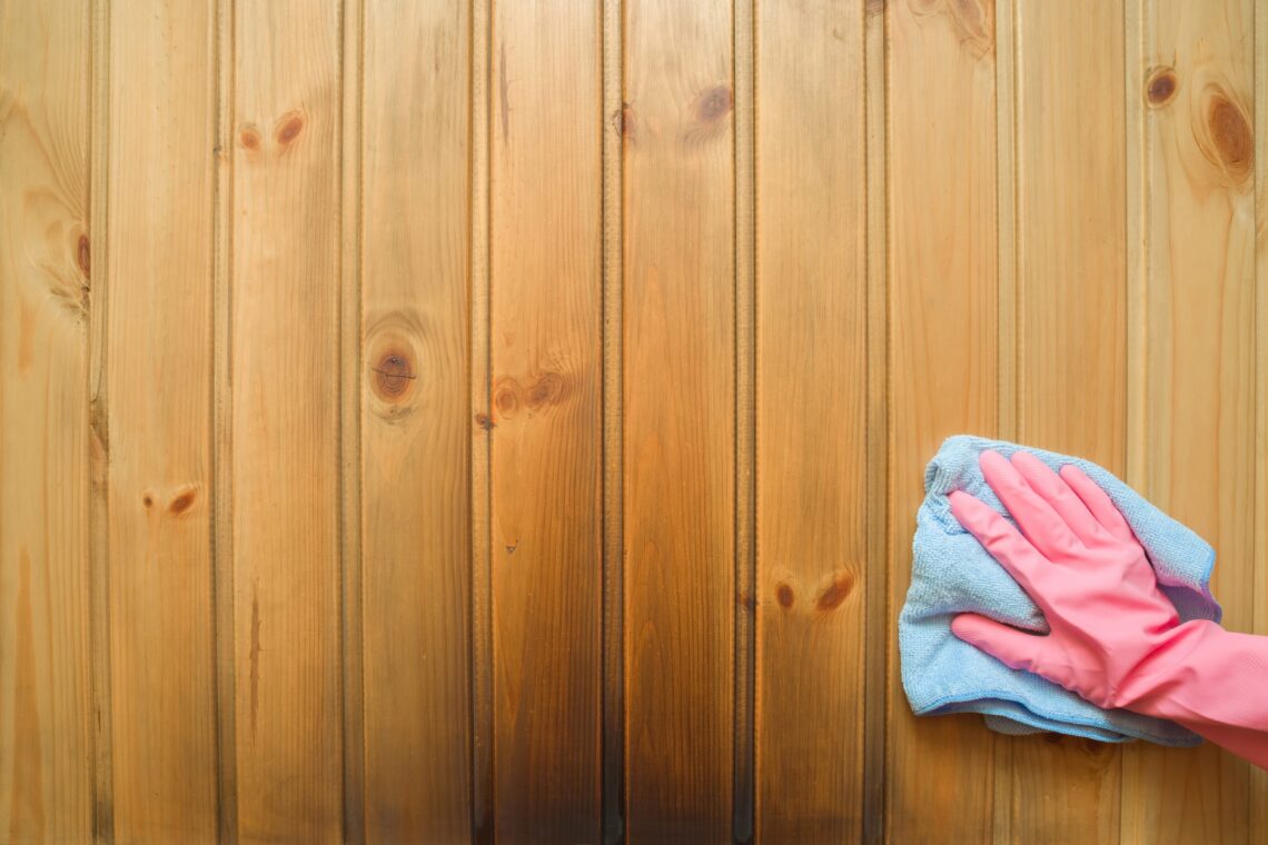 Hand cleaning a wooden sauna with a towel.