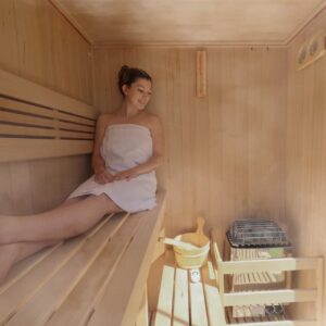 Woman in a towel inside a wooden sauna smiling.