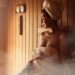 Woman wearing a towel inside a wet wooden sauna.