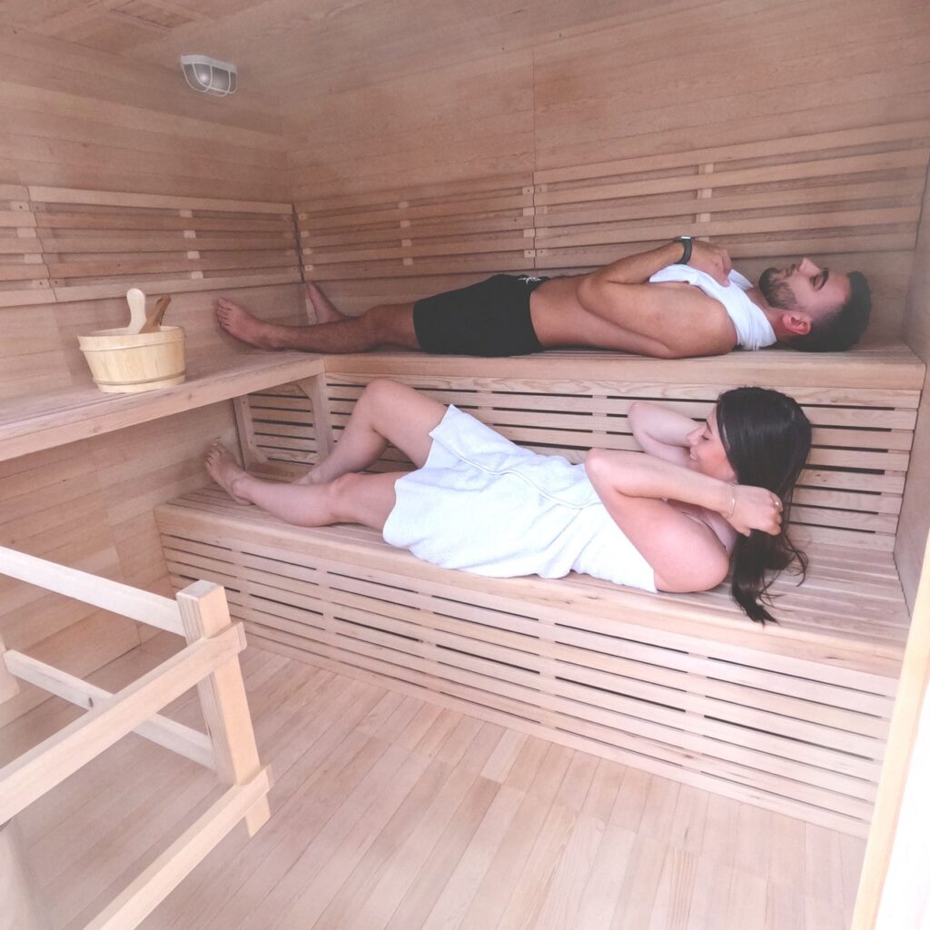 Man and woman lying inside a wooden wet sauna.